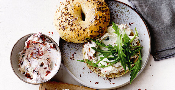 Leinsamen-Bagels mit Tomaten-Oliven-Frischkäse und Rucola